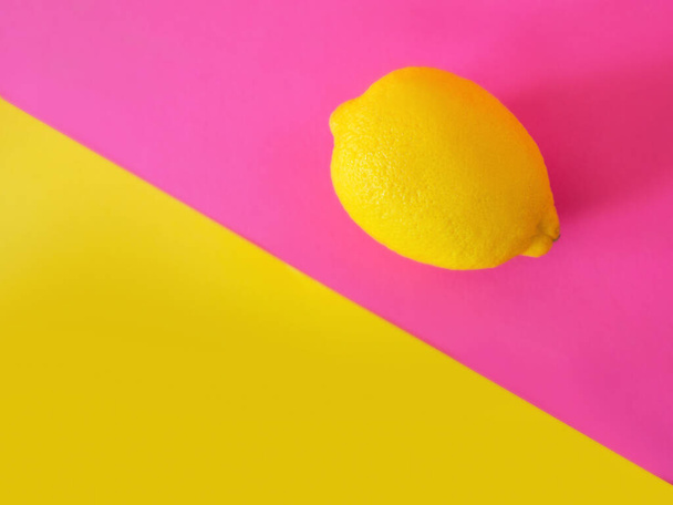 stylish yellow lemon on pink and yellow background. Citrus, summer, fruits concept - Valokuva, kuva