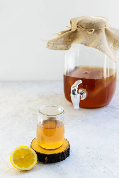 Homemade kombucha tea with lemon in a glass on a gray table. Healthy drink. - Фото, изображение