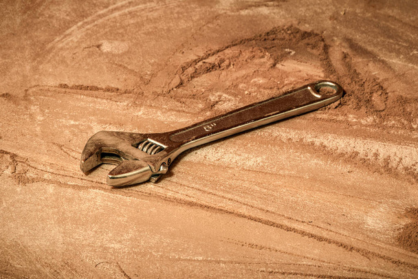 una llave inglesa en el banco de trabajo llena de polvo y suciedad de madera
.  - Foto, Imagen