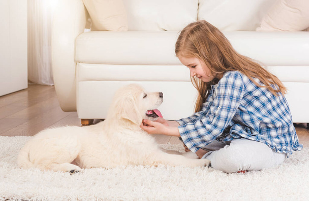 Girl sitting with retriever puppy at home - Фото, зображення