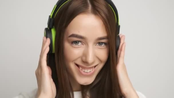 An office worker at his desk listens to music in stylish green headphones. Happy manager at work - Materiaali, video