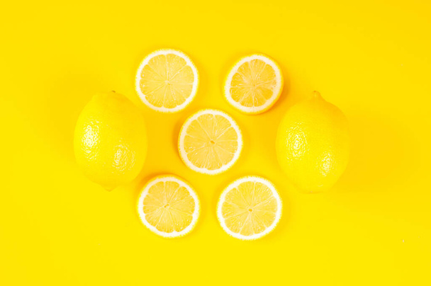 Citrons sur fond jaune vif. Concept de fond citron, plat. Citronnelle, agrumes concept minimal. Fond créatif composé de citron et de feuilles. Vue du dessus. - Photo, image