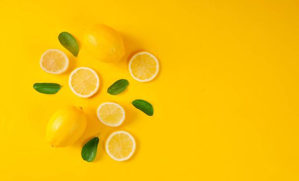 Citrom és zöld levelek élénk sárga háttérrel. Étel koncepció, lapos fektetés. Citrom gyümölcs, citrus minimális koncepció, C-vitamin Alkotó háttér készült citrom és levél. Felülnézet. - Fotó, kép