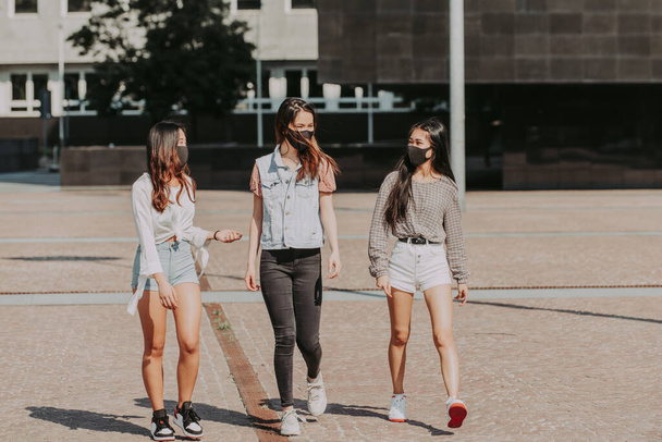 Asian girls with face masks bonding outdoors during pandemic and social distance era - Concepts about quarantine, prevention and covid-19 - Zdjęcie, obraz