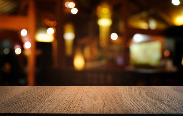 Restoranın soyut bulanık arka planının önündeki boş, siyah ahşap masa. Ürünlerinizi görüntülemek ya da montajlamak için kullanılabilir.  - Fotoğraf, Görsel