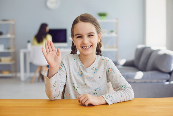 Kid girl looking at web camera waving hand in living room - Φωτογραφία, εικόνα