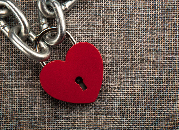 κλειδωμένη καρδιά σχήμα λουκέτο με αλυσίδα χάλυβα σε γκρι λινό ύφασμα - Φωτογραφία, εικόνα