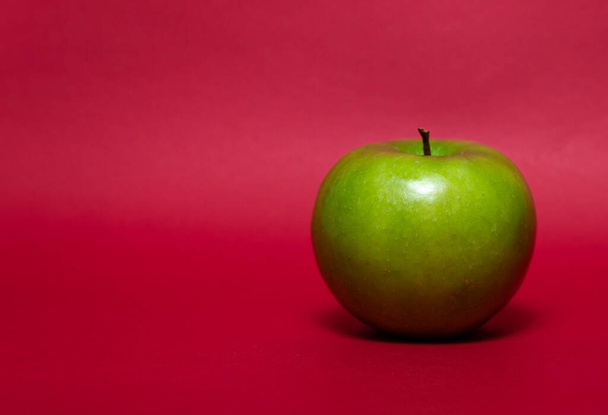 Groene appel op een rode achtergrond.Vers fruit. - Foto, afbeelding