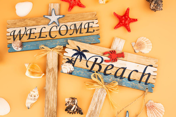 Wooden signs welcome beach, starfish and shells on yellow background. - Foto, Bild