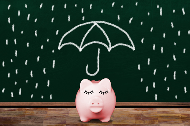Економія на дощовий день з рожевим скарбничкою в класі з крейдяною ілюстрацією парасольки, що захищає свиню від дощу. Концепція фінансової безпеки, заощаджень, страхового покриття, управління багатством тощо
. - Фото, зображення
