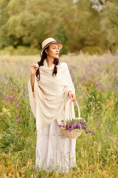 Woman in a hat picking lilac flowers in a wicker basket on the meadow. - Fotografie, Obrázek