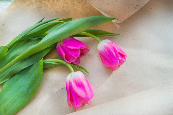 Un ramo de tres tulipanes rosados en papel Kraft. La vista desde arriba. Una copia del espacio. Plantilla presentación
. - Foto, imagen