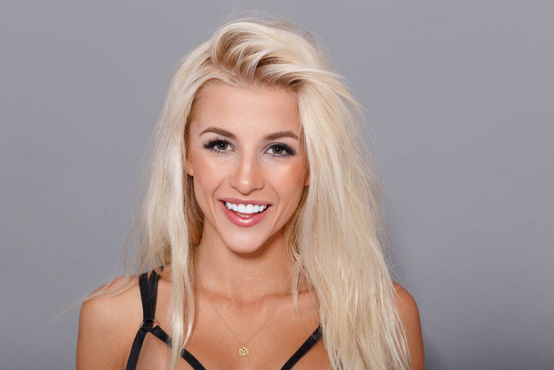 Beauty frontal portrait. Sexy smiling blonde girl on gray background, looking at camera. - Photo, Image