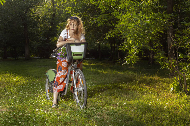 Reife Frau fährt Fahrrad im Abendpark. Abgelegener Spaziergang - Foto, Bild