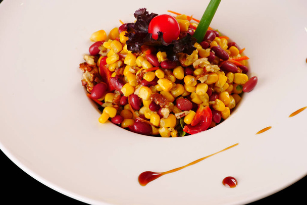 Bean salad. Salad with beans, corn, walnuts, meat, tomatoes. Black background - Photo, Image