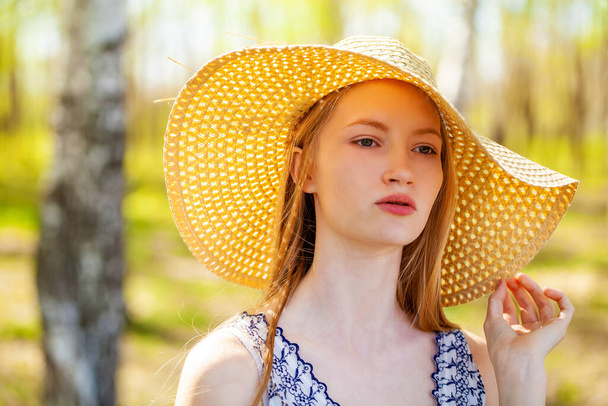 Close up portrait of a young blonde woman with a straw hat - 写真・画像