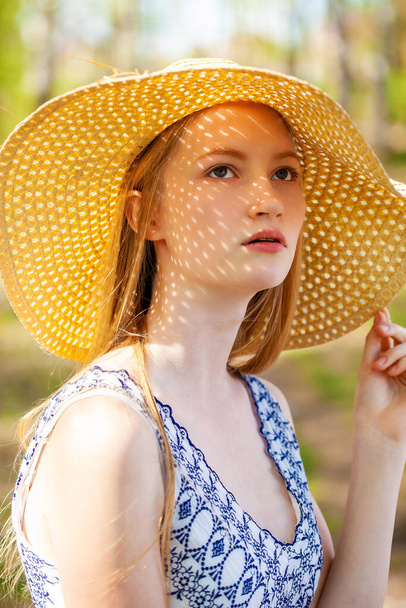 Close up portrait of a young blonde woman with a straw hat - Fotó, kép