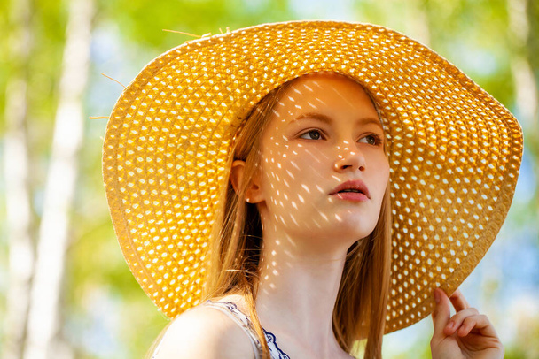 Close up portrait of a young blonde woman with a straw hat - Foto, Imagen