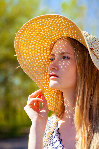 Close up portrait of a young blonde woman with a straw hat - Foto, Imagem