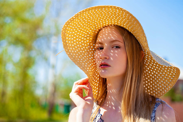 Close up portrait of a young blonde woman with a straw hat - Foto, Imagen