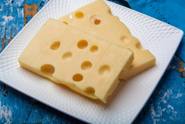 Twee blokken Franse emmentale halfharde kaas van dichtbij - Foto, afbeelding