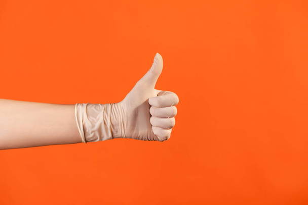 Profile side view closeup of human hand in white surgical gloves showing like or thumbs up. indoor, studio shot, isolated on orange background. - Valokuva, kuva