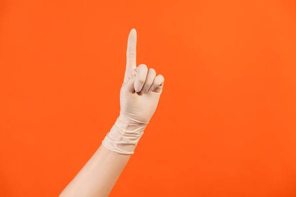 Profile side view closeup of human hand in white surgical gloves showing number one with finger or showing up side. indoor, studio shot, isolated on orange background. - Fotografie, Obrázek