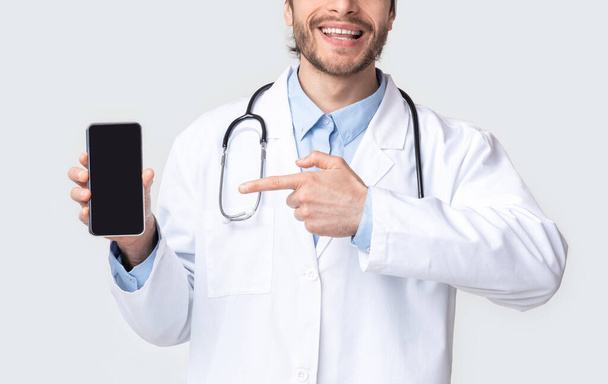 Médico profesional mostrando teléfono inteligente en blanco
 - Foto, imagen