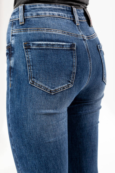 girl in jeans shows jeans back pockets on a white background close-up, blue jeans - 写真・画像