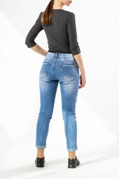 girl in jeans shows jeans on a white background close-up, blue jeans - Фото, изображение