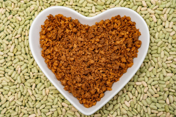 Love vegan and vegetarian food concept, plant based minced meat in heart shaped plate on soya beans background close up - Photo, Image