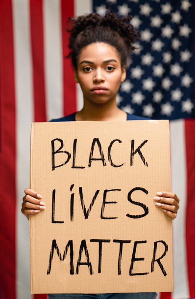Африканська американка стоїть з плакатом "Чорне життя". - Фото, зображення