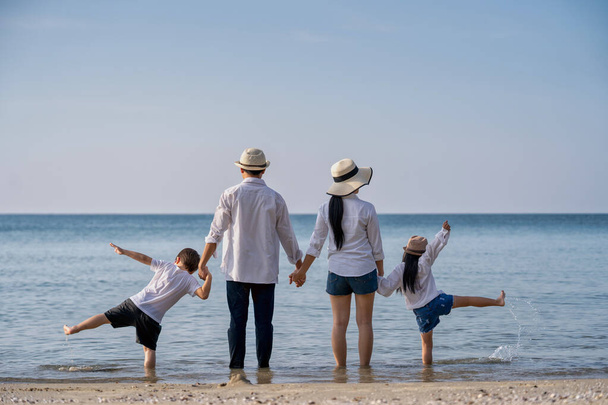 Pais com crianças desfrutando de férias na praia
 - Foto, Imagem
