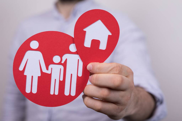 A closeup shot of a person holding a red family and a house paper cut-outs under the lights - Photo, image