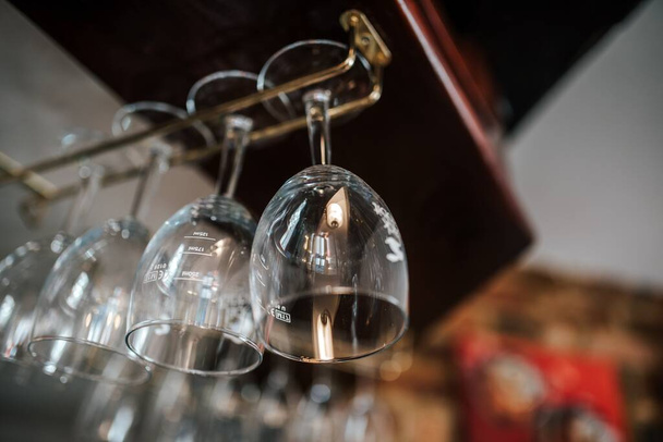A shot of wine glasses hanging from the metal beams in a bar - Фото, зображення