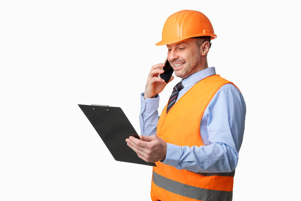 Építési munkás beszél telefonon Holding mappa felett fehér háttér - Fotó, kép