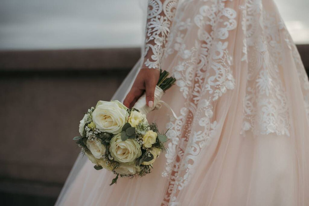 The bride wearing a beautiful wedding dress and holding her wedding day's bouquet of beautiful roses - Foto, immagini