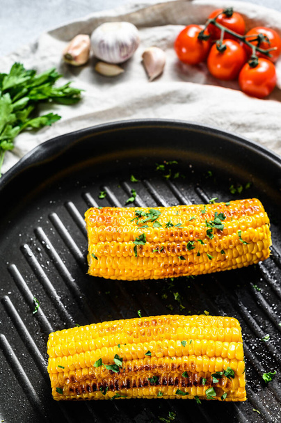 Organikus grillezett kukorica egy serpenyőben. Biogazdasági zöldségek. Szürke háttér. Felülnézet. - Fotó, kép