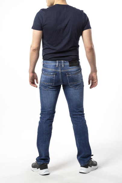 man in jeans, denim pants close up on white background, blue jeans, blue t-shirt - Фото, изображение