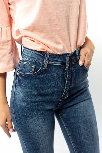girl in jeans shows off jeans on white background close up, blue jeans - Foto, Imagem