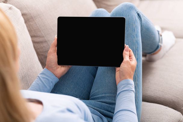 Educación en el sofá. Mujer viendo lecciones de vídeo en la tableta con pantalla vacía
 - Foto, Imagen