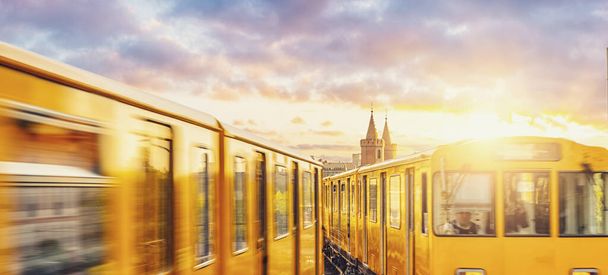 U-Bahn berlinese con ponte Oberbaum sullo sfondo in una luce dorata al tramonto con nuvole drammatiche, Berlino Friedrichshain-Kreuzberg
 - Foto, immagini
