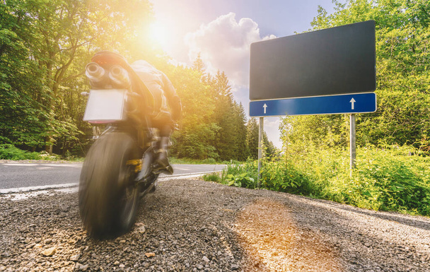 мотоцикл починає їздити і керувати порожньою лісовою дорогою під час подорожі на мотоциклі. Порожній рекламний щит з копійкою для вашого окремого тексту
.  - Фото, зображення