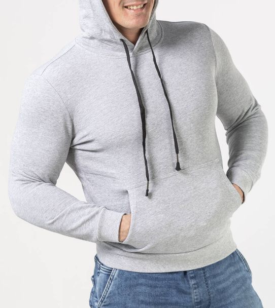 a man in a grey hoodie and blue jeans on a white background - Фото, изображение