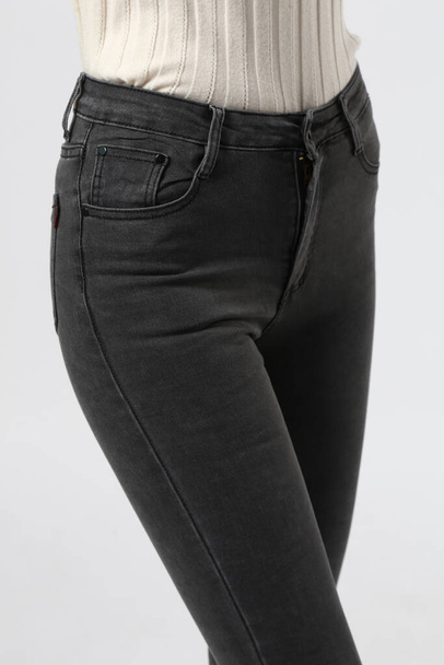 girl in jeans shows off jeans on a white background close-up, black jeans - Φωτογραφία, εικόνα