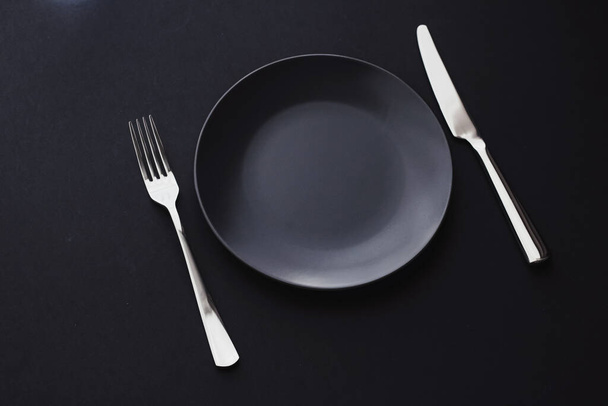 Empty plates and silverware on black background, premium tableware for holiday dinner, minimalistic design and diet - Photo, Image