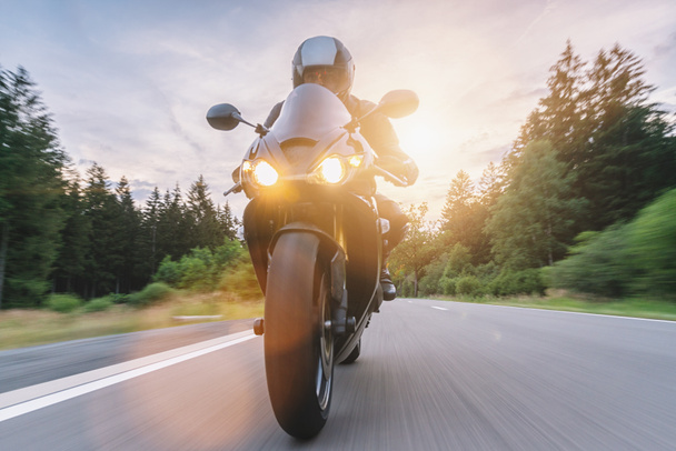 andar en moto al atardecer conducir en la carretera vacía en un viaje en motocicleta. copyspace para su texto individual
. - Foto, Imagen