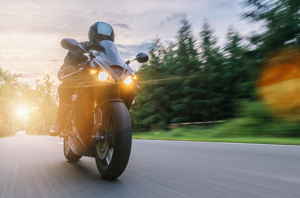 мотоцикл на лісовій дорозі їде на заході сонця. їзда на порожній дорозі на мотоциклі. копіювання вашого окремого тексту
. - Фото, зображення
