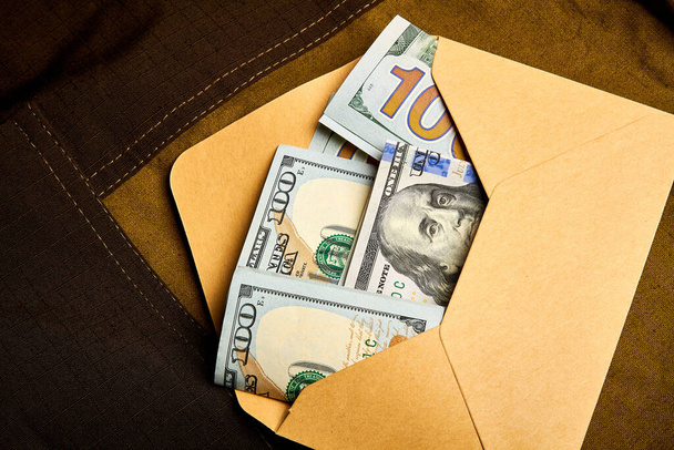 Hundred dollar bills in a paper envelope. Receiving money in an envelope. Black bookkeeping. Giving a bribe. - Φωτογραφία, εικόνα
