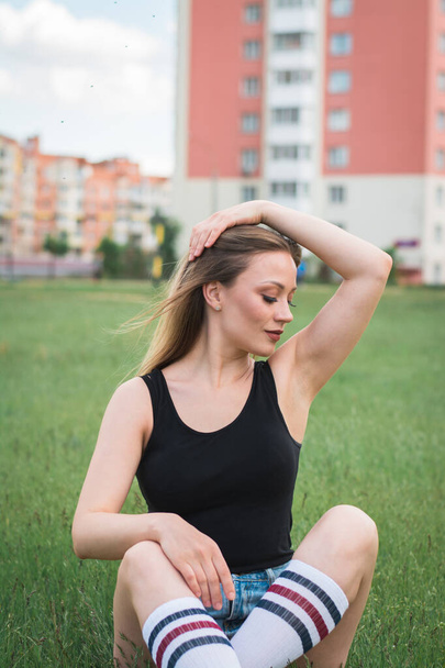 fitness girl in sportswear sitting on green grass a summer day - Foto, afbeelding